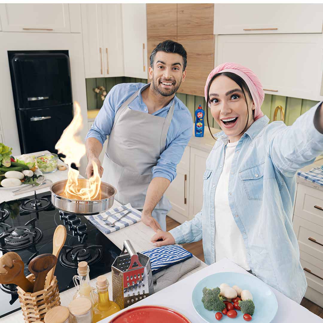 A man and a woman cooking food on a stove