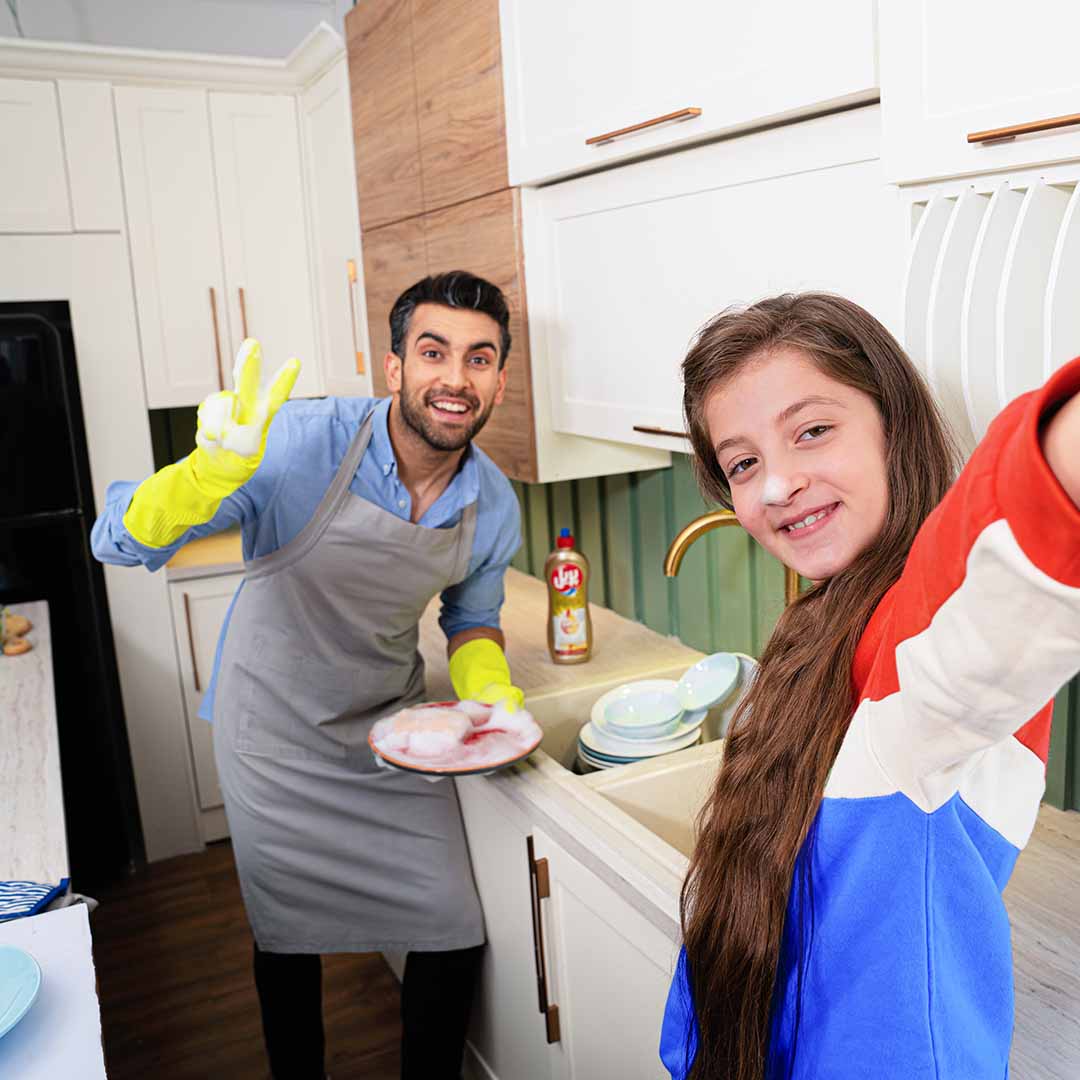 A father and daughter together in the kitchen doing the dishes
